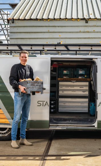 Medewerker laadt een houten krat in een bestelbus voor levering