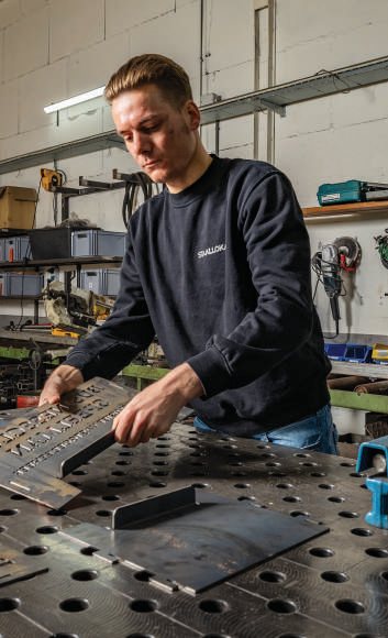Medewerker bewerkt stalen onderdelen aan een geperforeerde lastafel