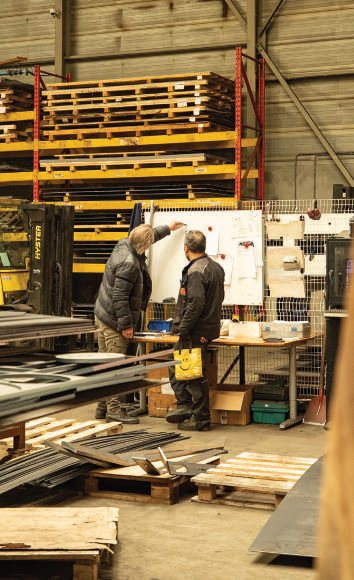 Magazijn met stellingen vol staalplaten waar medewerkers materiaal selecteren