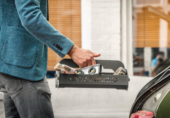 Man laadt een gevuld stalen geschenkkrat in de kofferbak van een auto