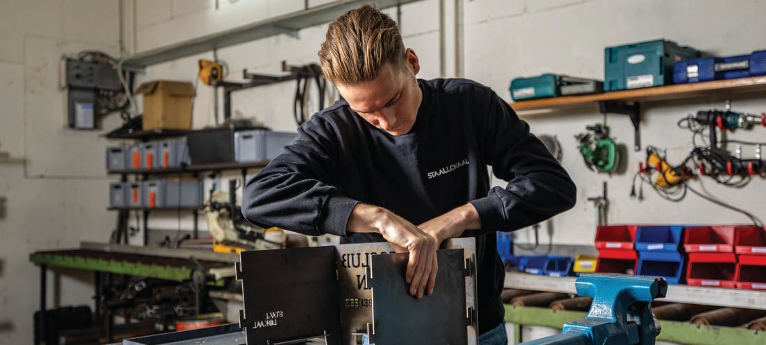 Medewerker zet een stalen geschenkkist in elkaar aan een werkbank in de werkplaats